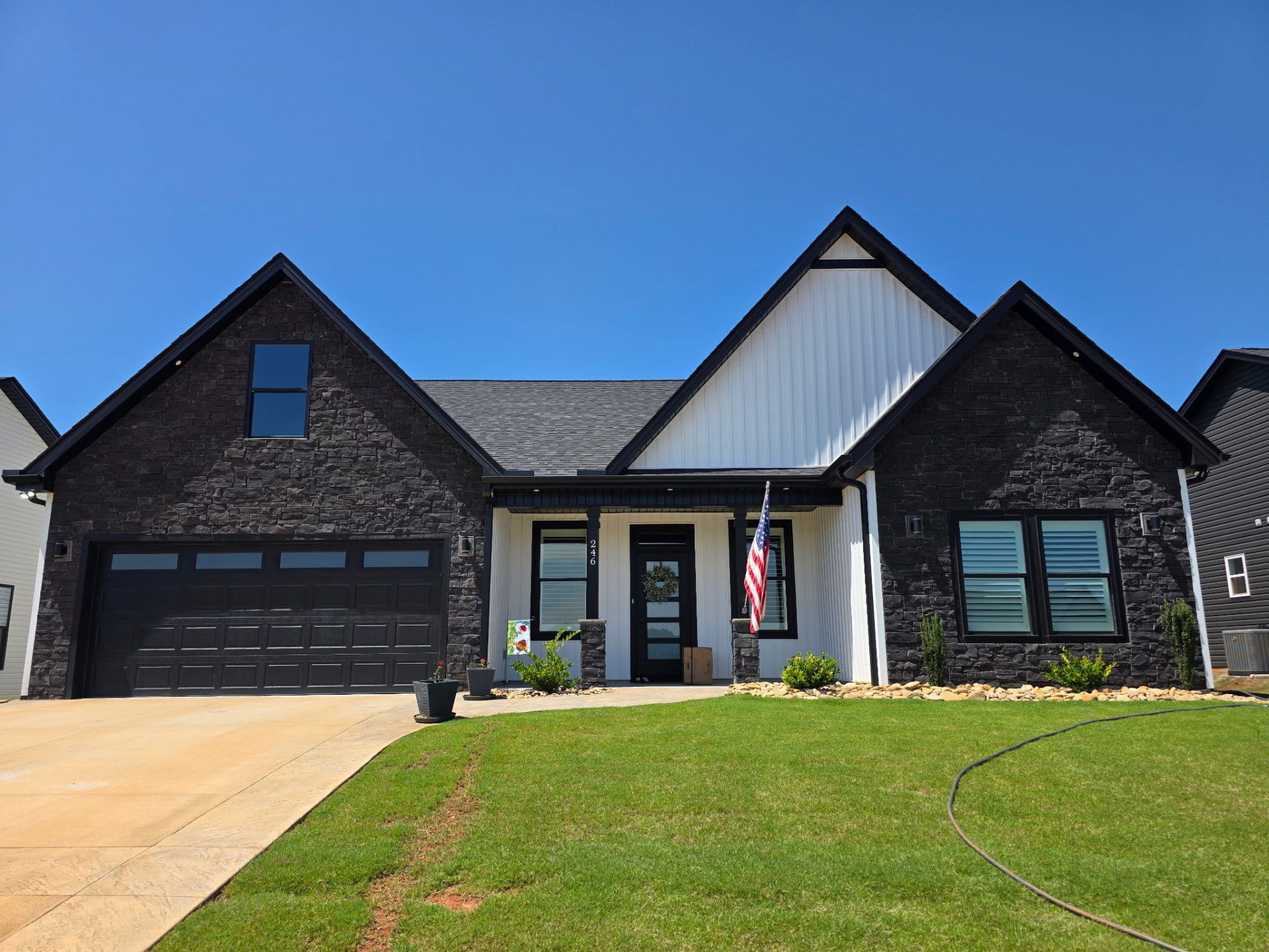 Ranch home with charcoal stacked stone facade and white board-and-batten entry