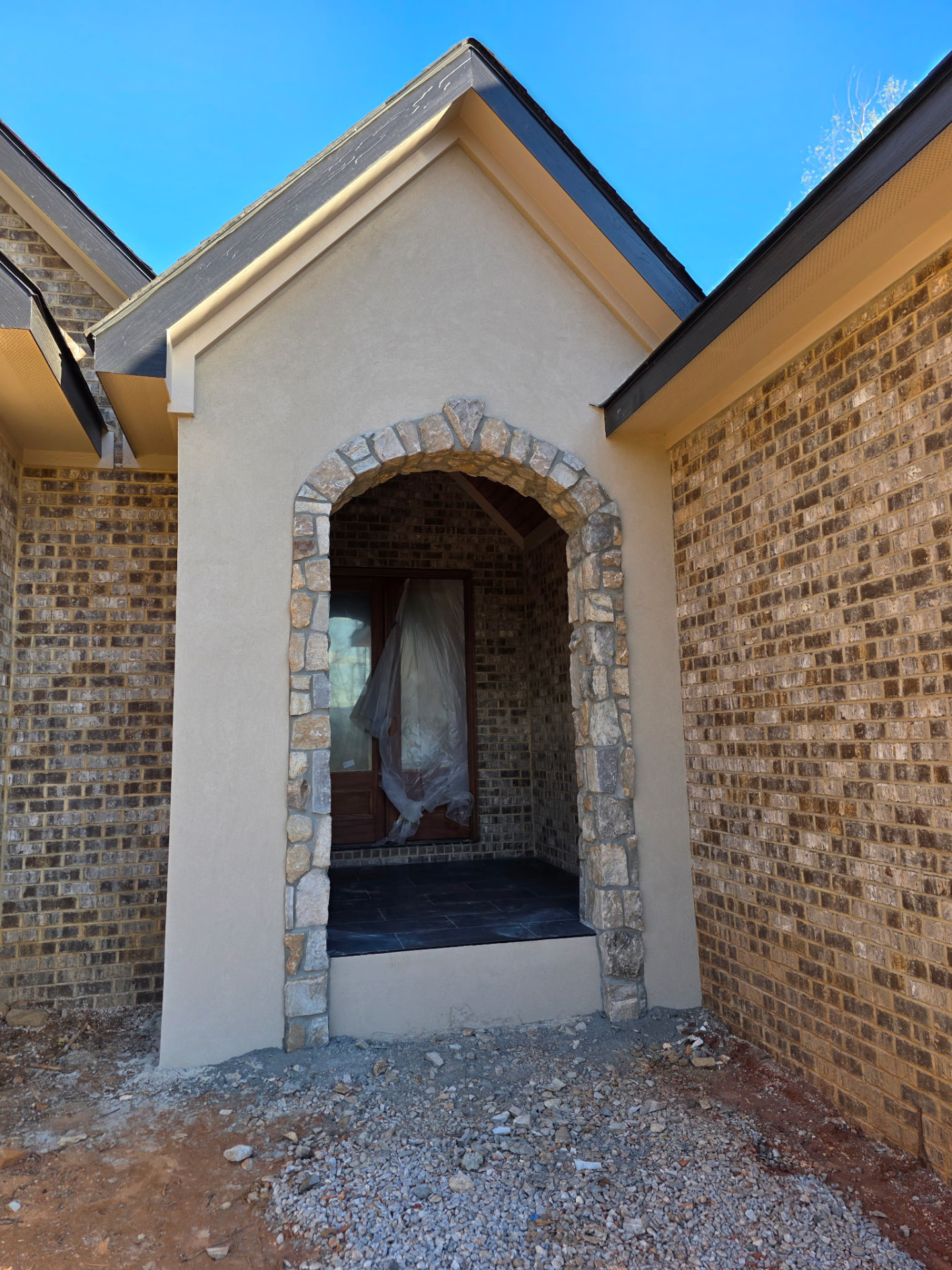 Stone arch entry framed by stucco and brick