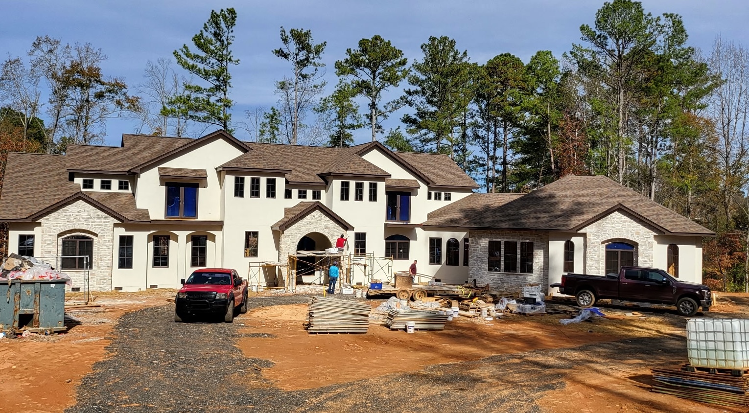 Large residential stucco home with stone accents under construction