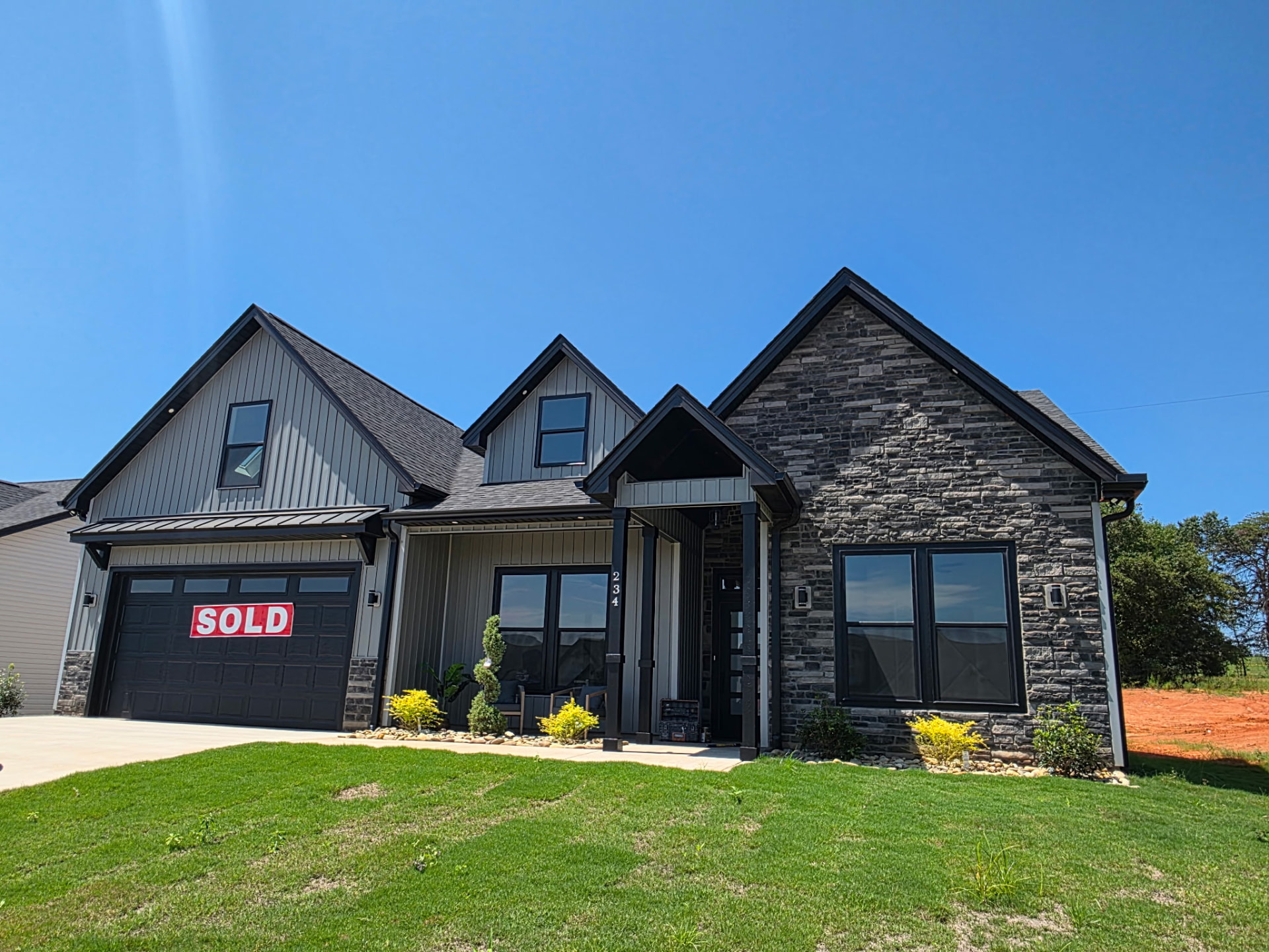 Charcoal home with gray stacked stone gable and covered entry