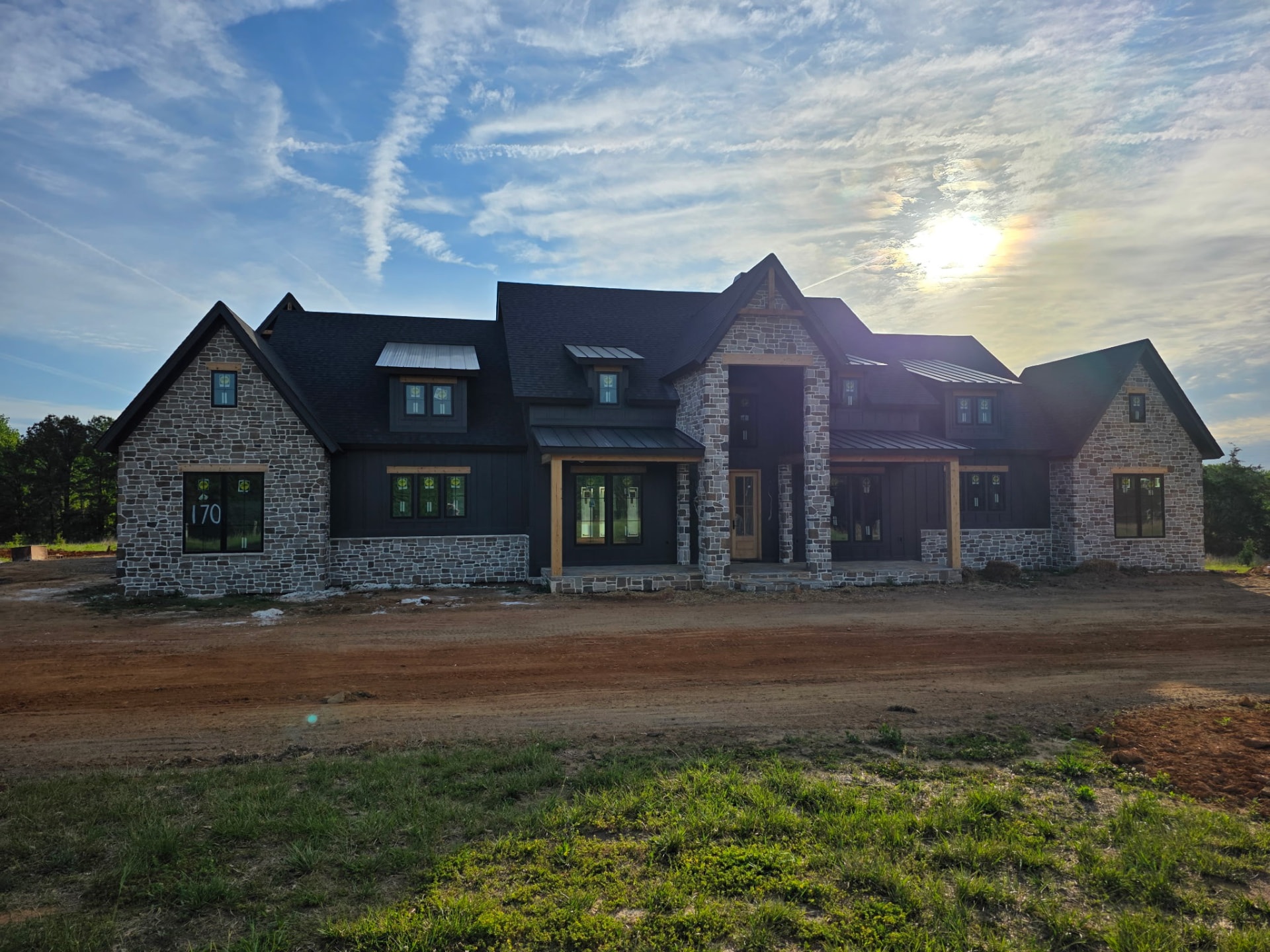 Large custom home with gray stone gables, board-and-batten siding, and a stone entry porch