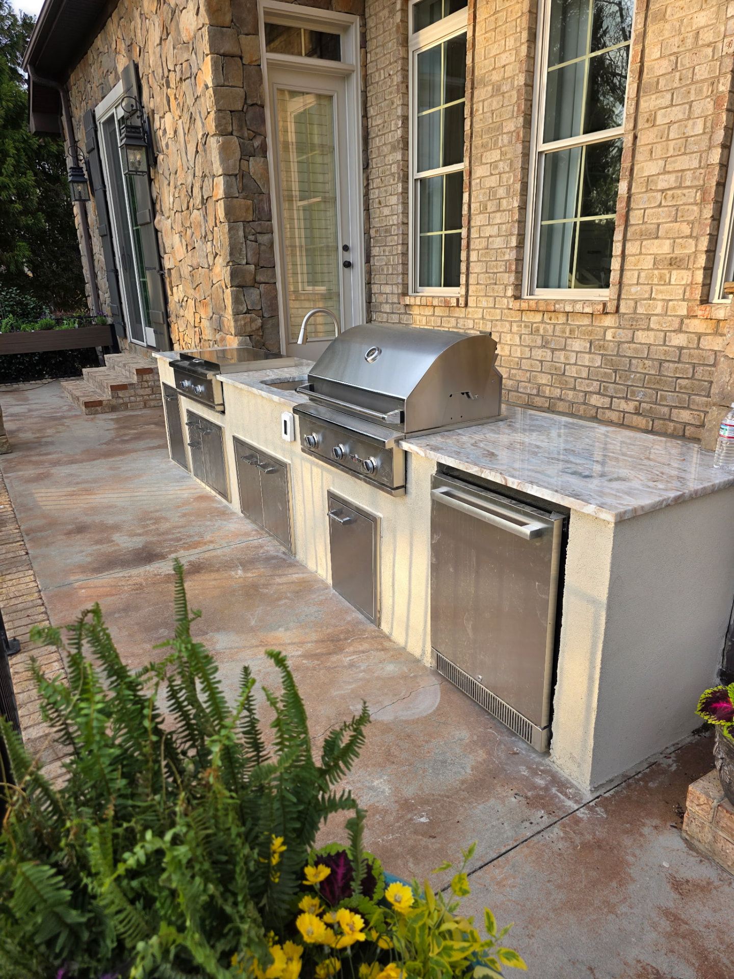 Outdoor kitchen with grill, cabinetry, stonework, and countertops