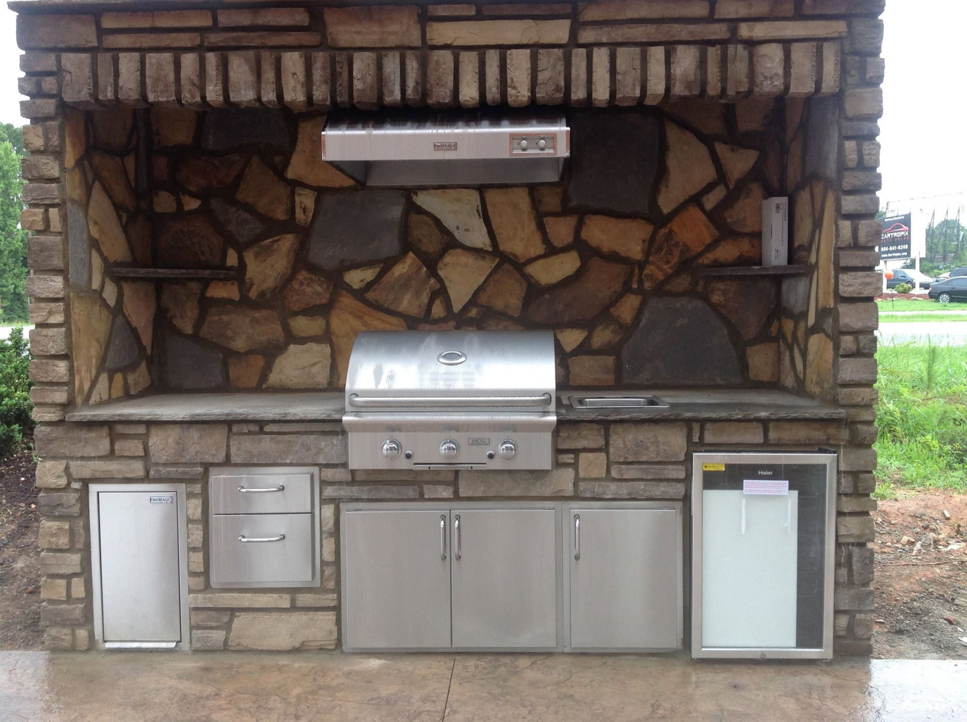 Close view of an outdoor kitchen with stonework and stainless steel appliances