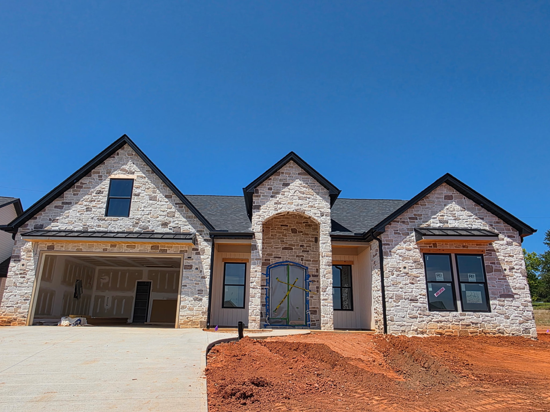 Full white and cream stone facade home with an arched stone entry